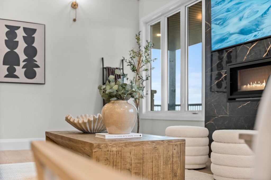 Modern living room featuring a wooden coffee table with a vase and decor, abstract wall art, fireplace, and large window with a view.